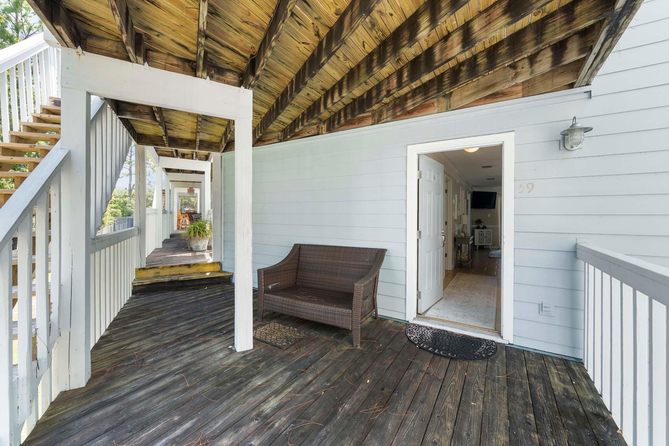 A wooden porch with a bench, a staircase, and a door leading inside.