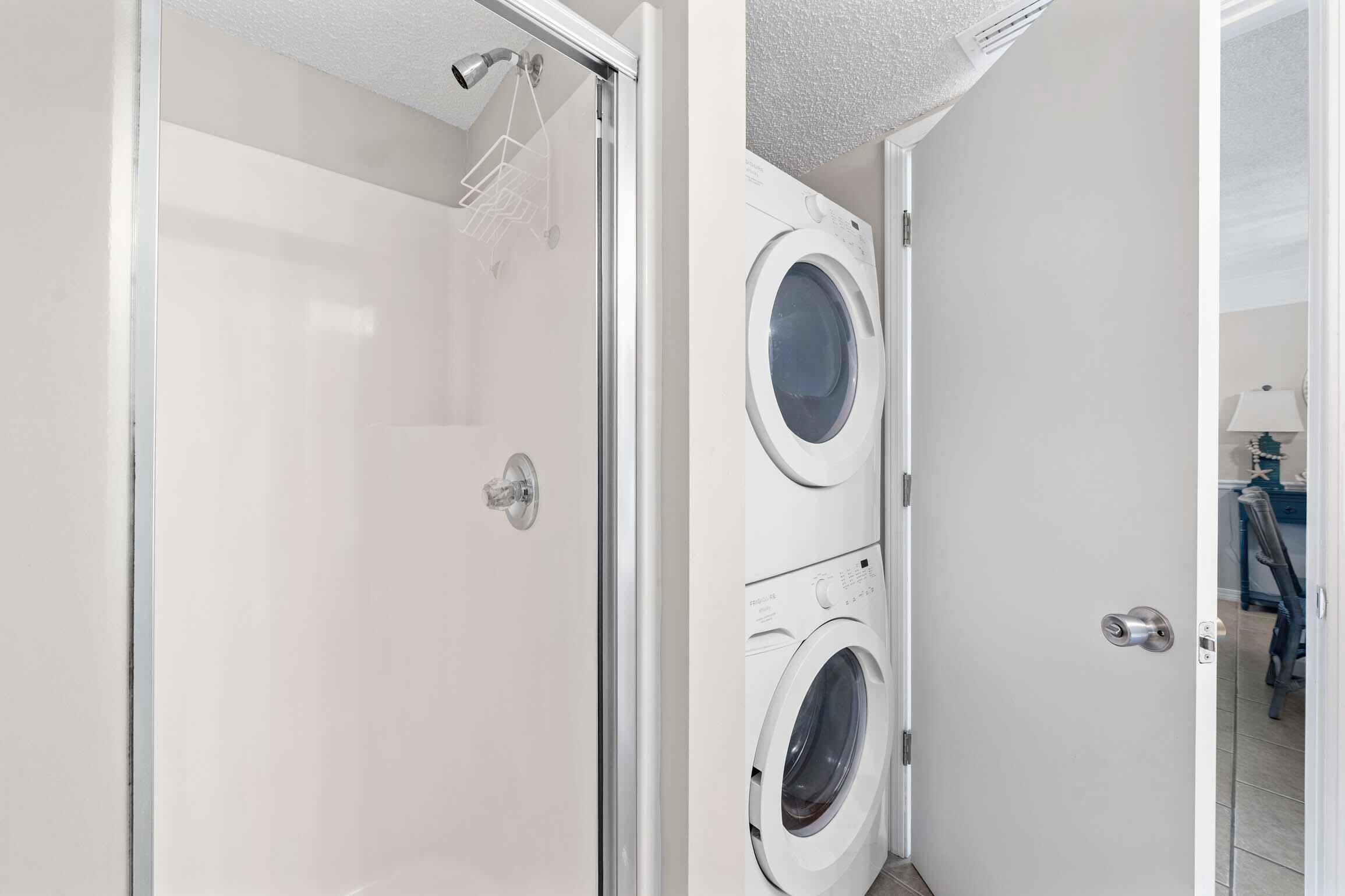 A laundry room with a glass shower enclosure and two front-loading washing machines.