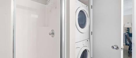 A laundry room with a glass shower enclosure and two front-loading washing machines.
