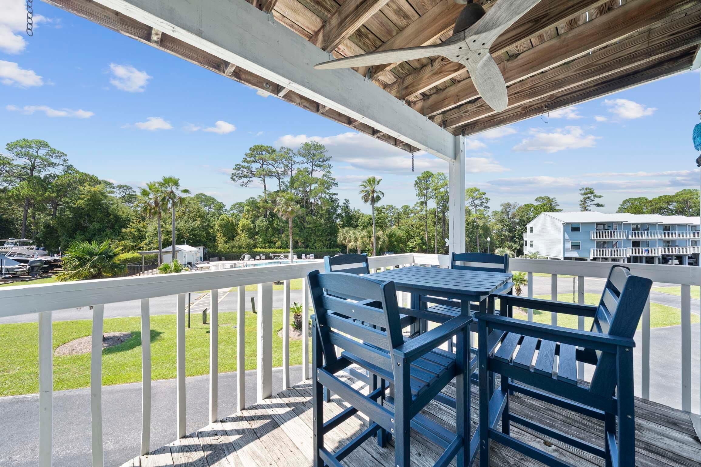 A covered outdoor area with a wooden deck, white railing, and a table with chairs.