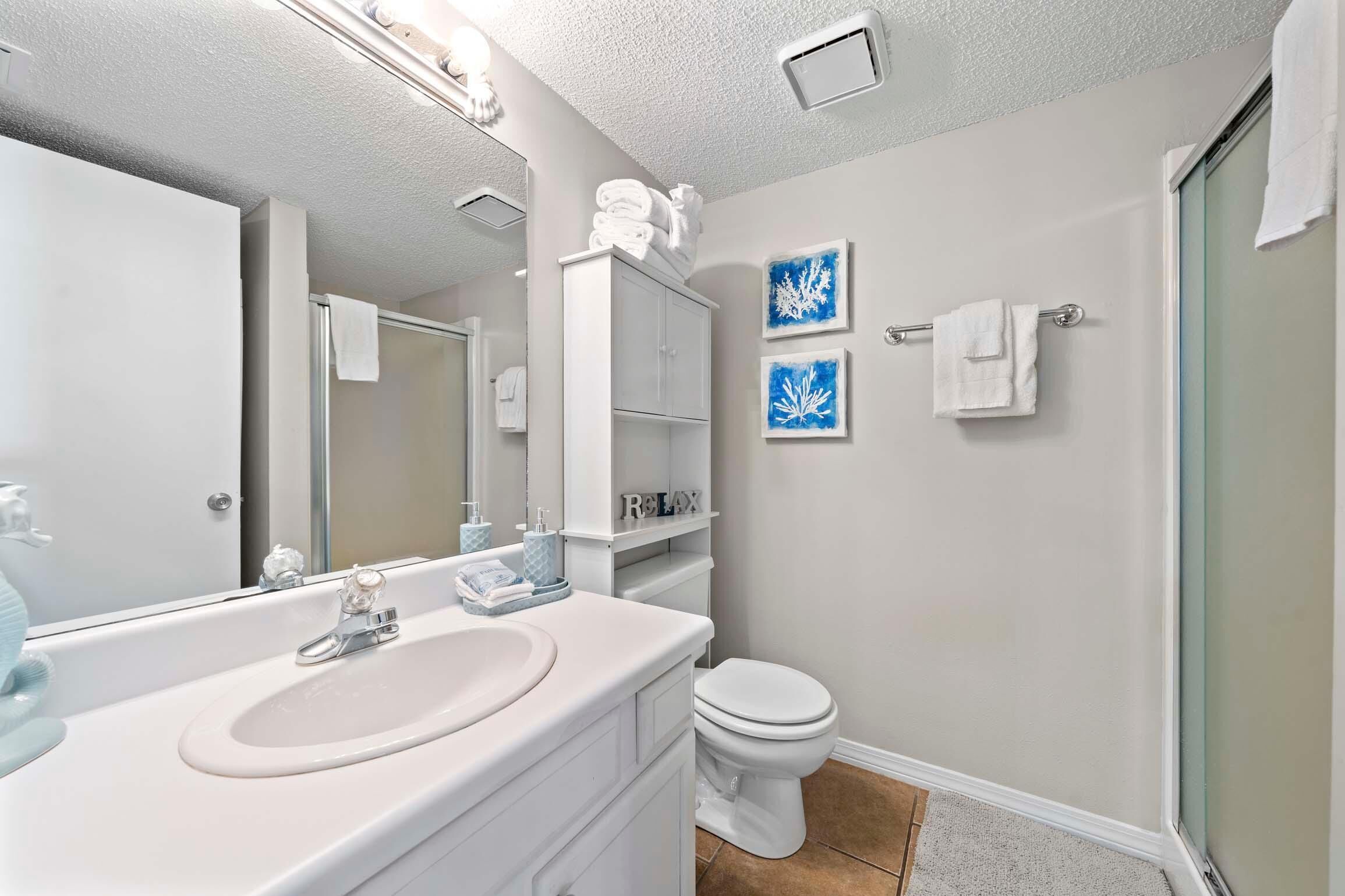 A bathroom with a white sink, a toilet, and a glass shower enclosure.