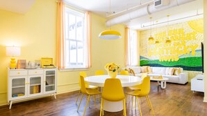 Un salón luminoso con una mesa redonda de comedor, sillas amarillas y un sofá blanco.