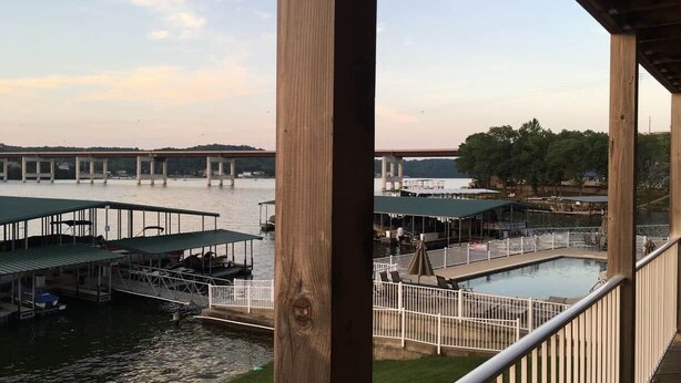 A waterfront property with a pool, dock area, and a view of a bridge in the background.