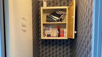 Une petite salle de bain comprenant des toilettes, un meuble au-dessus des toilettes et un mur orné d’un motif géométrique.