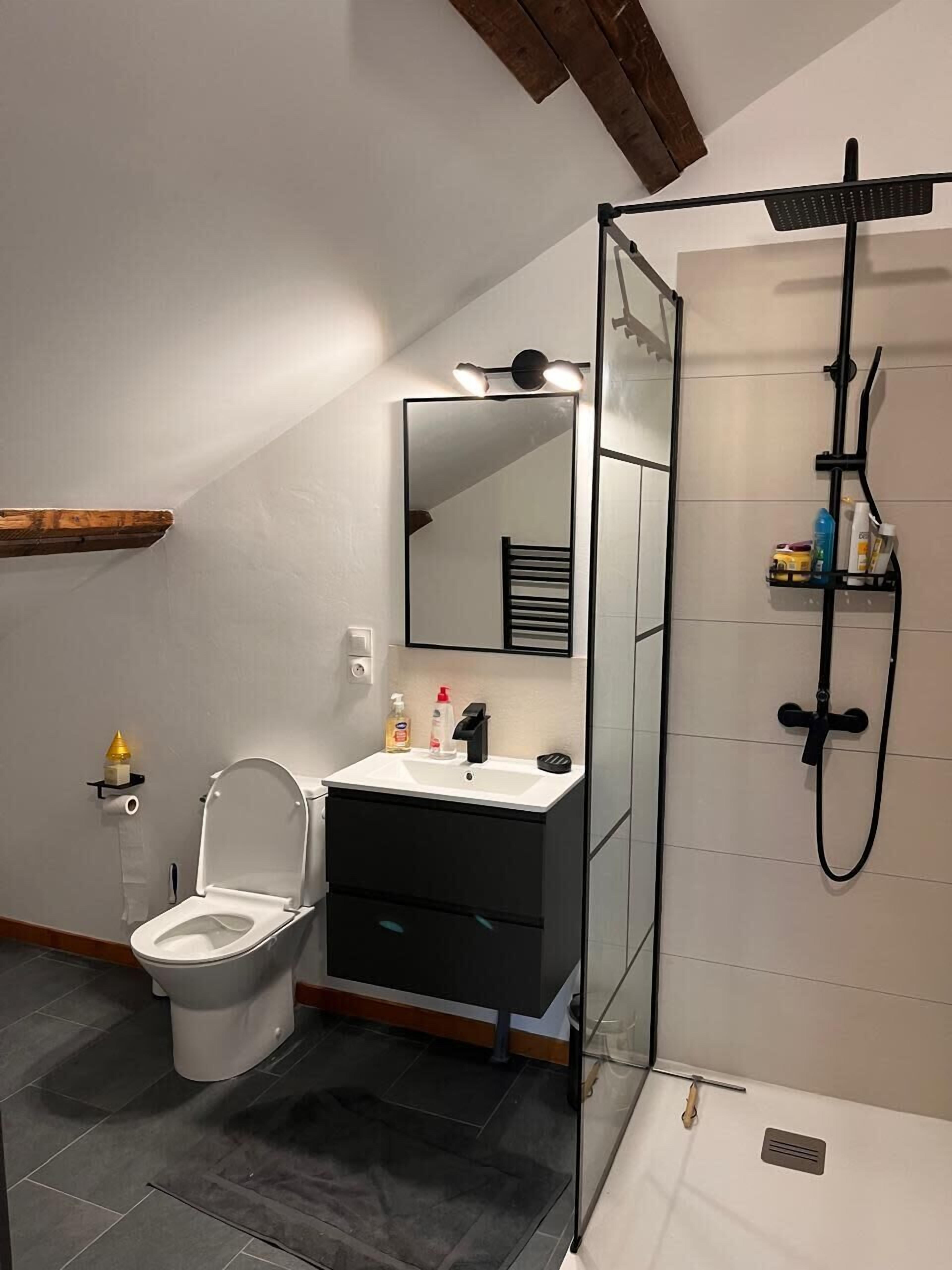 A modern bathroom with a toilet, sink, and shower.