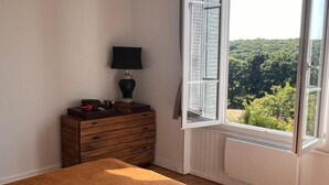 Un dormitorio con cama, cómoda, lámpara y ventana con persiana abierta.