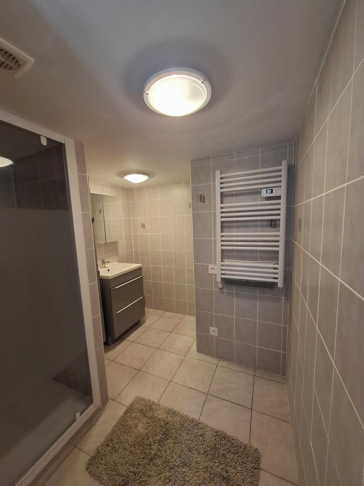 Een moderne badkamer met een douchecabine van glas, een ingebouwd wastafelmeubel en een handdoekrek.
