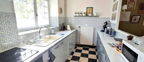Une cuisine avec un carrelage à motifs, une fenêtre, un évier et un four à micro-ondes.
