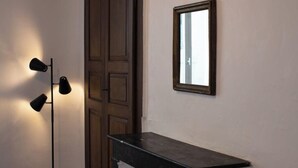 Un couloir avec un lampadaire noir, une porte en bois et un petit comptoir noir.