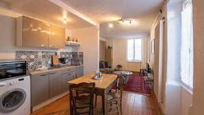 Une cuisine compacte équipée d’un lave-linge, d’une table à manger avec des chaises et d’un tapis rouge.