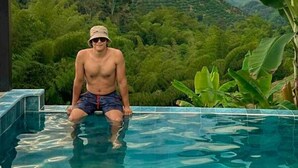 A man sitting in a pool with a scenic view of hills and a sunset in the background. - AREWÁ Biohabitat (Pijao)