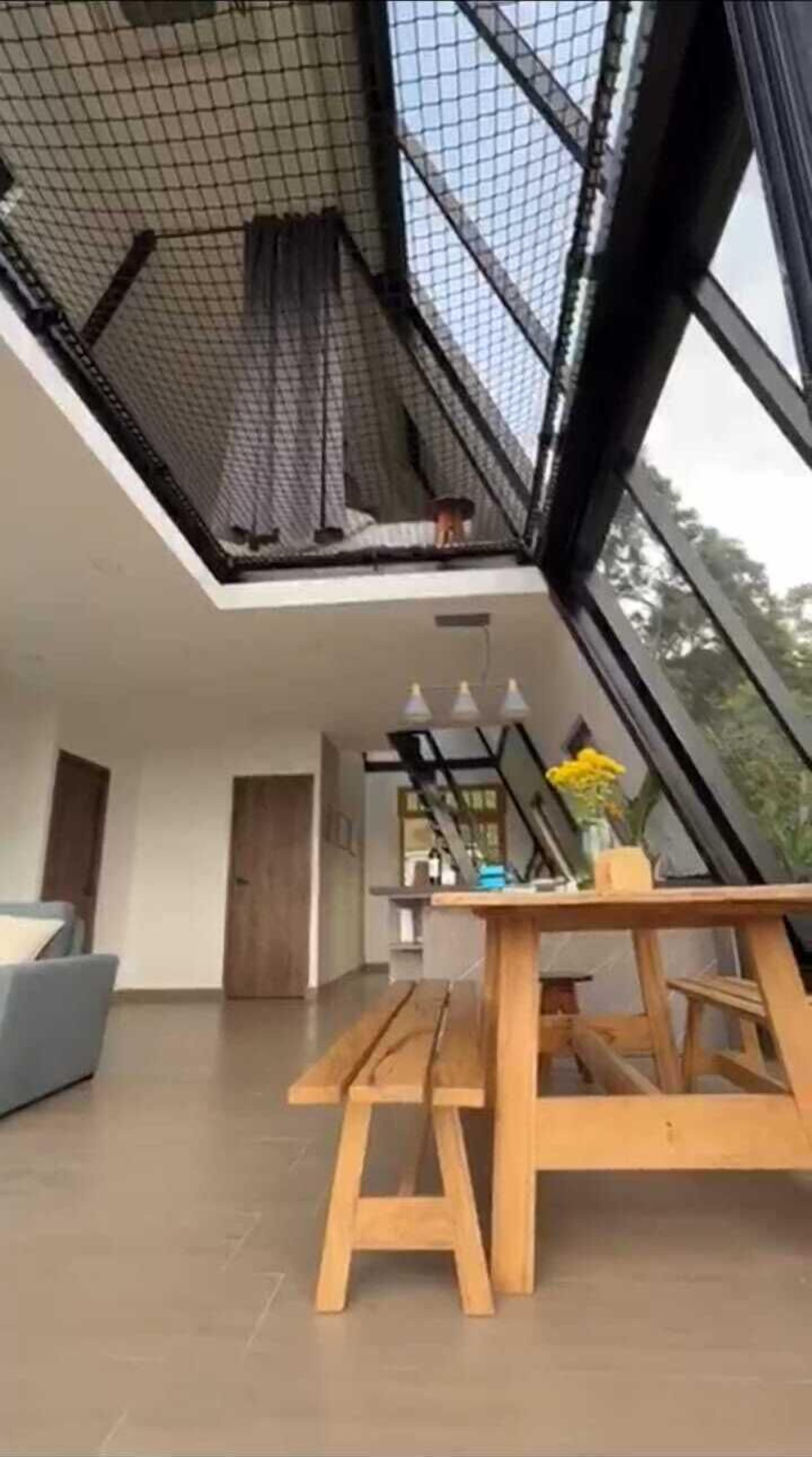 Een modern interieur met een hoge plafond, grote ramen en een houten eettafel.