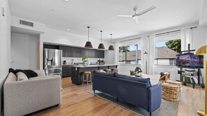 A modern kitchen with a central island, a dining area with a blue sofa, and a living room with a grey sofa. - 2 Condos-8 Min to Broadway-Balcony-5 King Beds (Nashville)