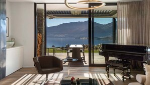 Ein modernes Wohnzimmer mit einem Flügel, einer gemütlichen Couch und einem Essbereich mit Panoramablick auf die Berge.