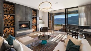 Ein modernes Wohnzimmer mit Kamin, Klavier und Bergblick.