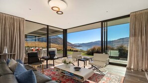 Ein modernes Wohnzimmer mit einer großen Glaswand und weiter Aussicht auf die Berge.