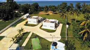 A residential area with two modern houses, a paved driveway, and a view of the ocean. - Two private beachfront houses, sleeps 12, kayaks, private heated pools (Cabo Rojo)