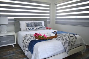 A neatly arranged bedroom with a bed, pillows, a bedside table, and a nightstand. - Two private beachfront houses, sleeps 12, kayaks, private heated pools (Cabo Rojo)