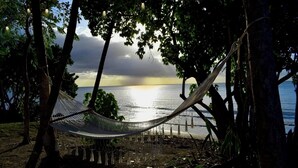 A hammock tied between trees overlooking a beach with a sunset in the background. - Two private beachfront houses, sleeps 12, kayaks, private heated pools (Cabo Rojo)