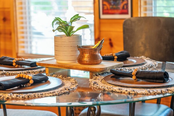 A dining table with placemats, a copper pot with a lemon, and a potted plant.