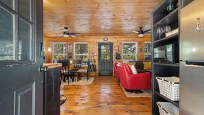 Un intérieur en bois comprenant un coin repas, un canapé rouge et un réfrigérateur.