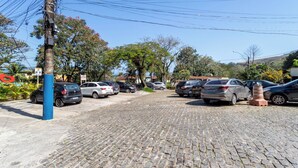 A parking area with cobblestone pavement and multiple cars parked. - Loft com Varanda e Vista Para o mar em Mangaratiba (Mangaratiba)