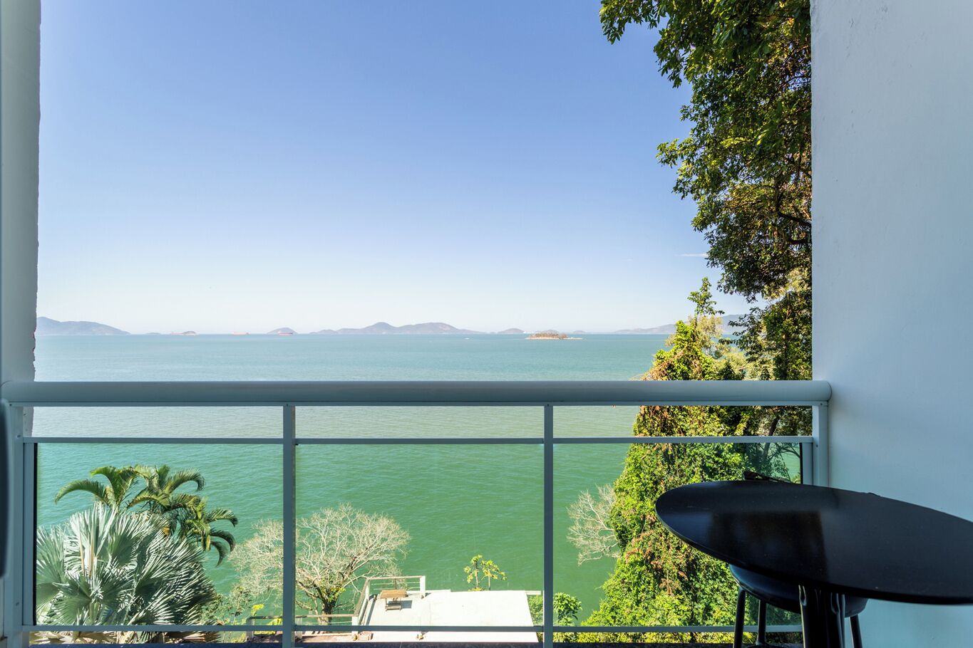 Quarto com grande janela com vista para um corpo de água e terra ao longe.