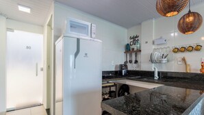 A modern kitchen with a white refrigerator, a built-in oven, a coffee machine, and a sink. - Loft com Varanda e Vista Para o mar em Mangaratiba (Mangaratiba)