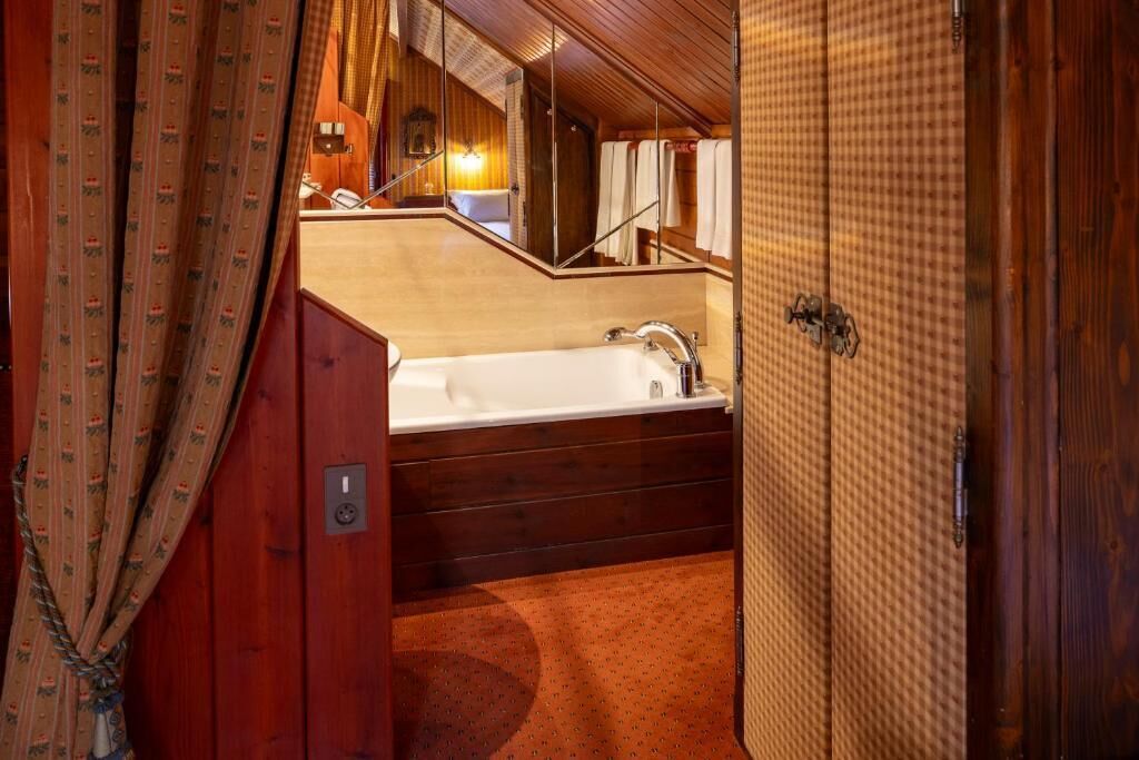 A wooden interior with a bathtub, a mirror, and a towel rack.