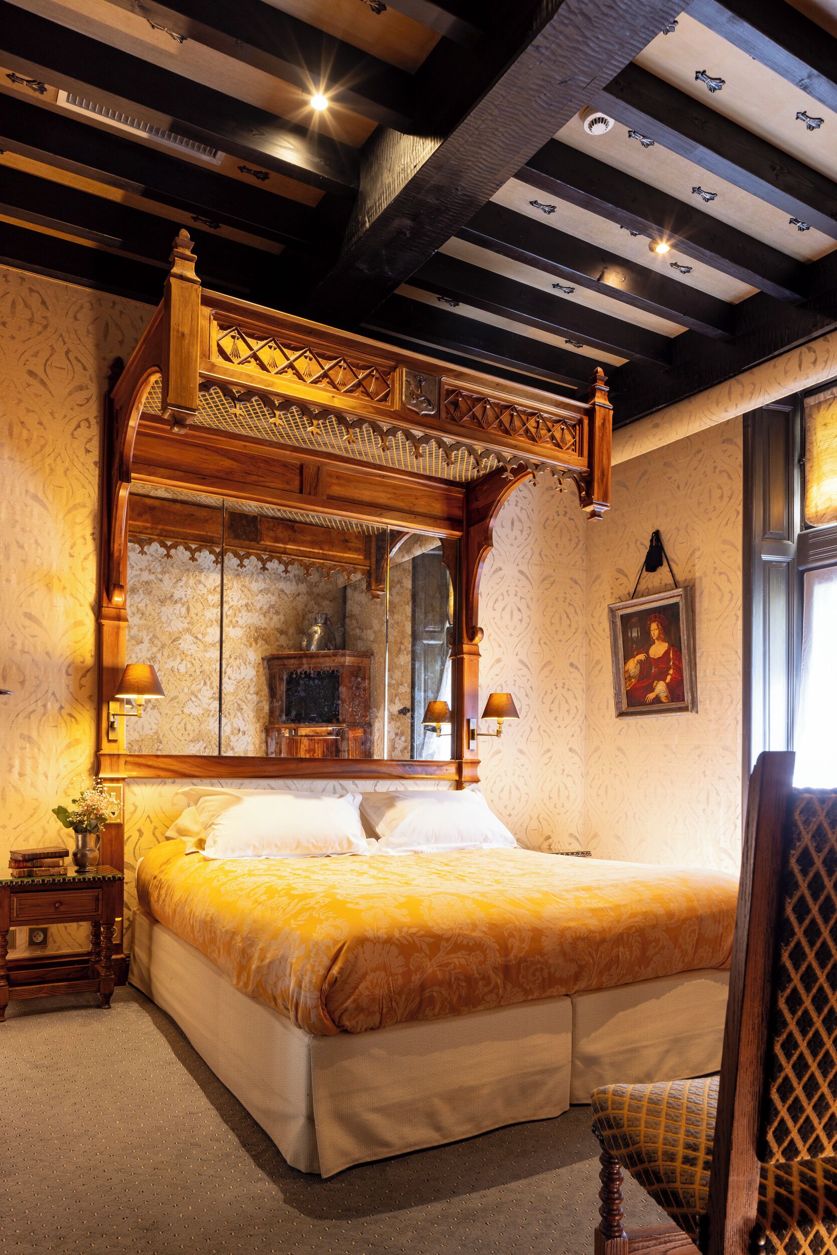 A traditional bedroom with a large bed, wooden headboard, and a mirror above the bed.