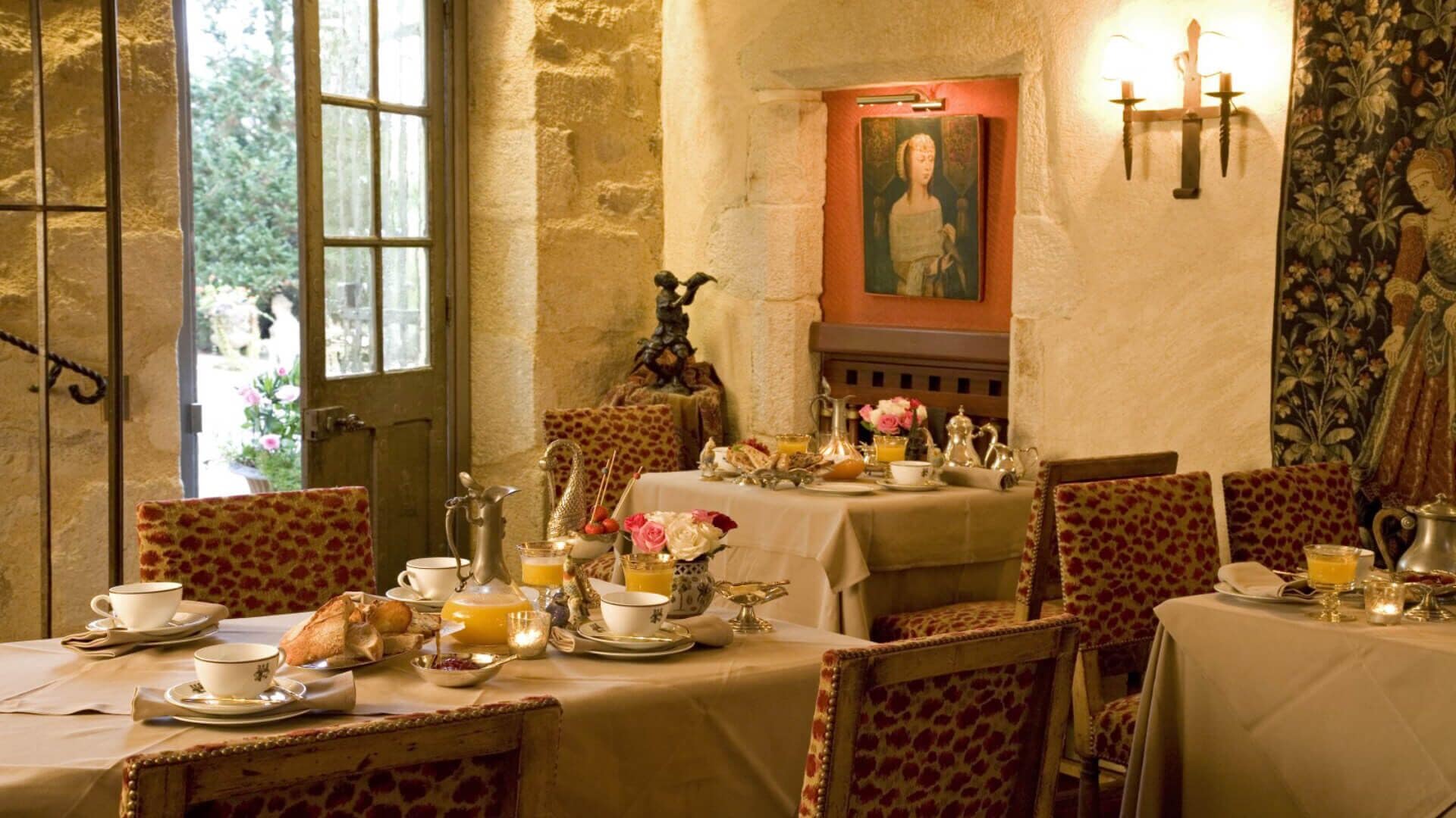 A dining area with a table set for breakfast, including bread, pastries, and tea.