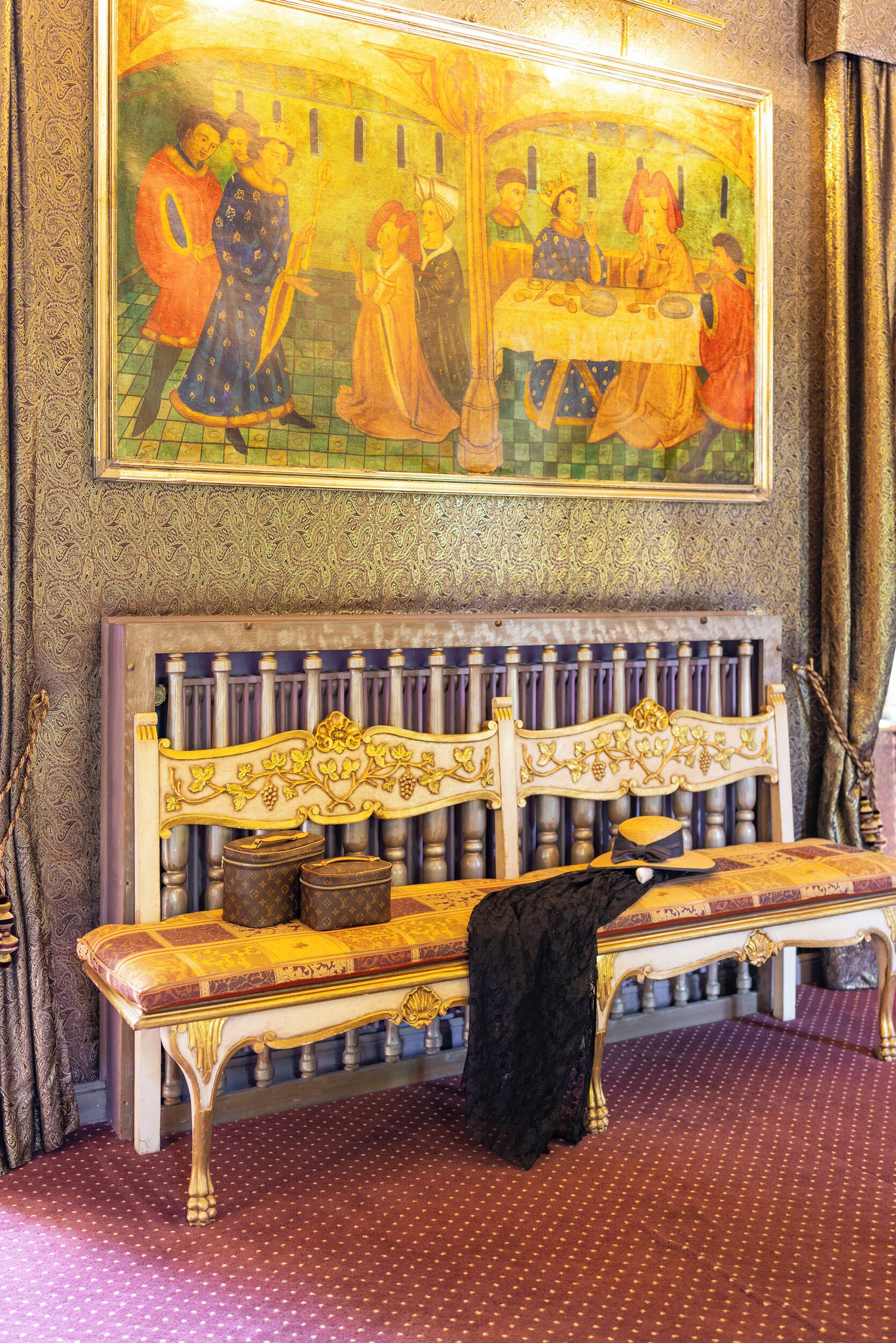 Una habitación con un banco, un cuadro y papel tapiz estampado.