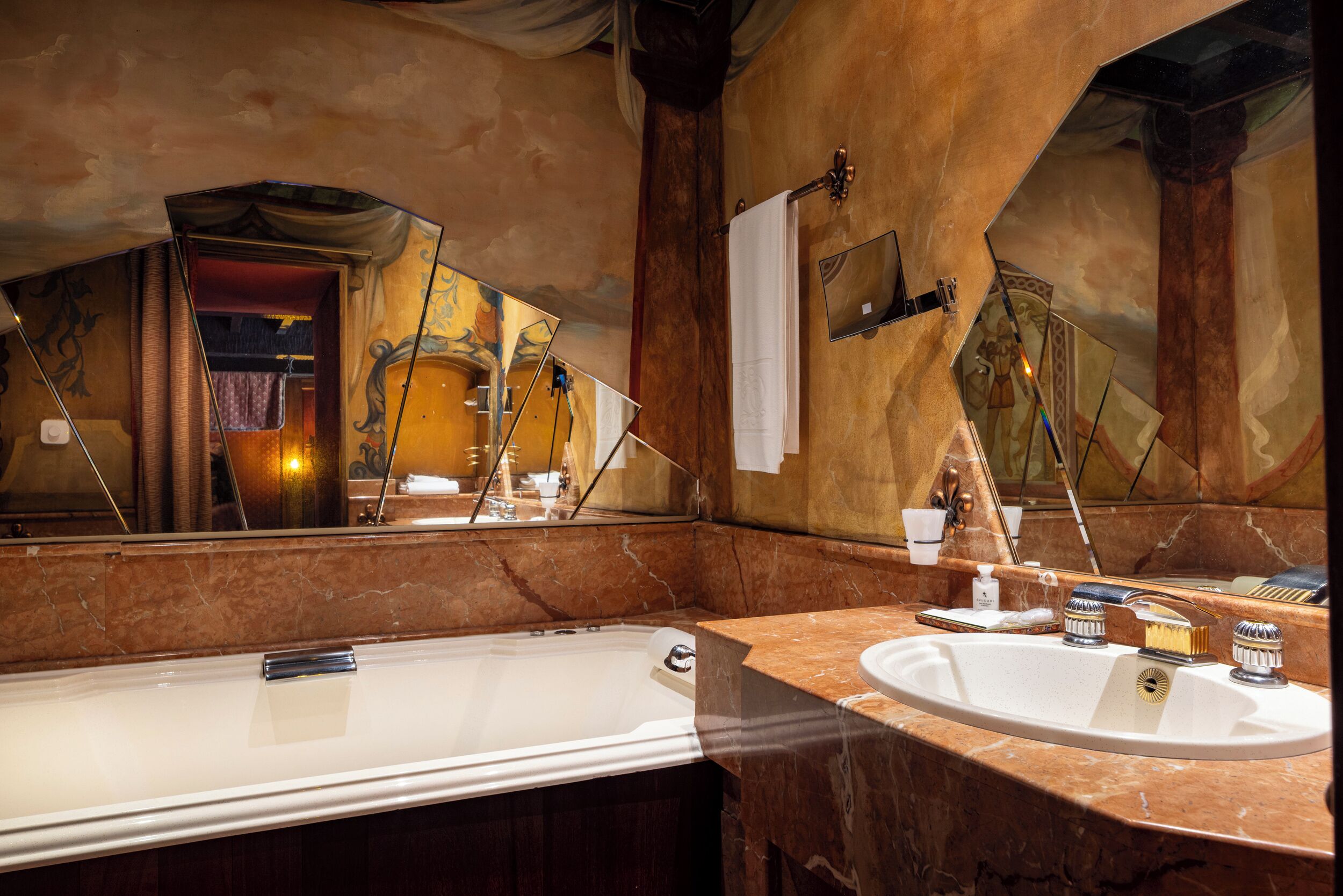 A bathroom with a large mirror, a bathtub, and a sink with toiletries.