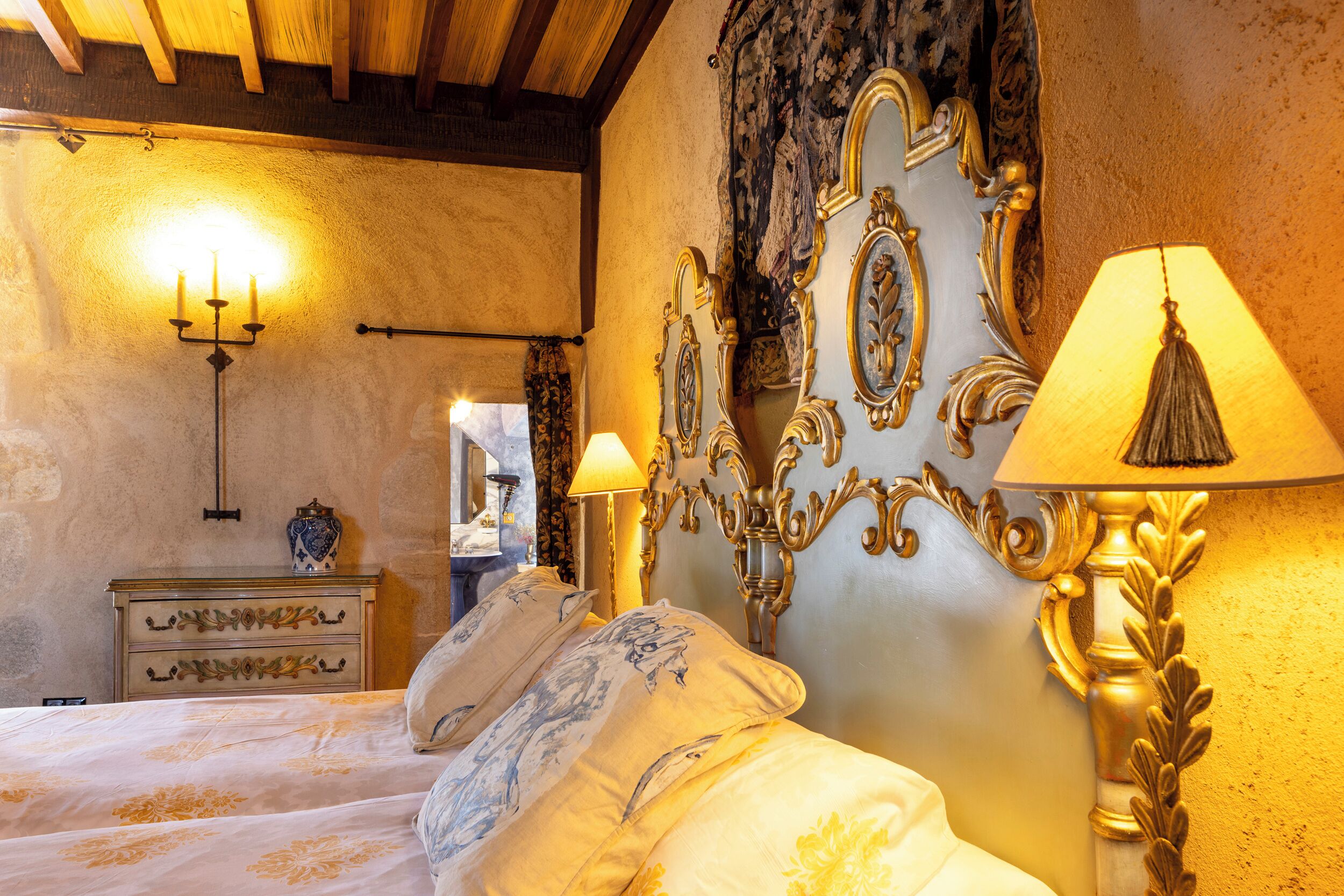 A bedroom with a bed, ornate wall decor, a candelabra, and a lamp.