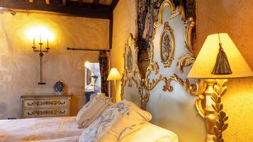 A bedroom with a bed, ornate wall decor, a candelabra, and a lamp.