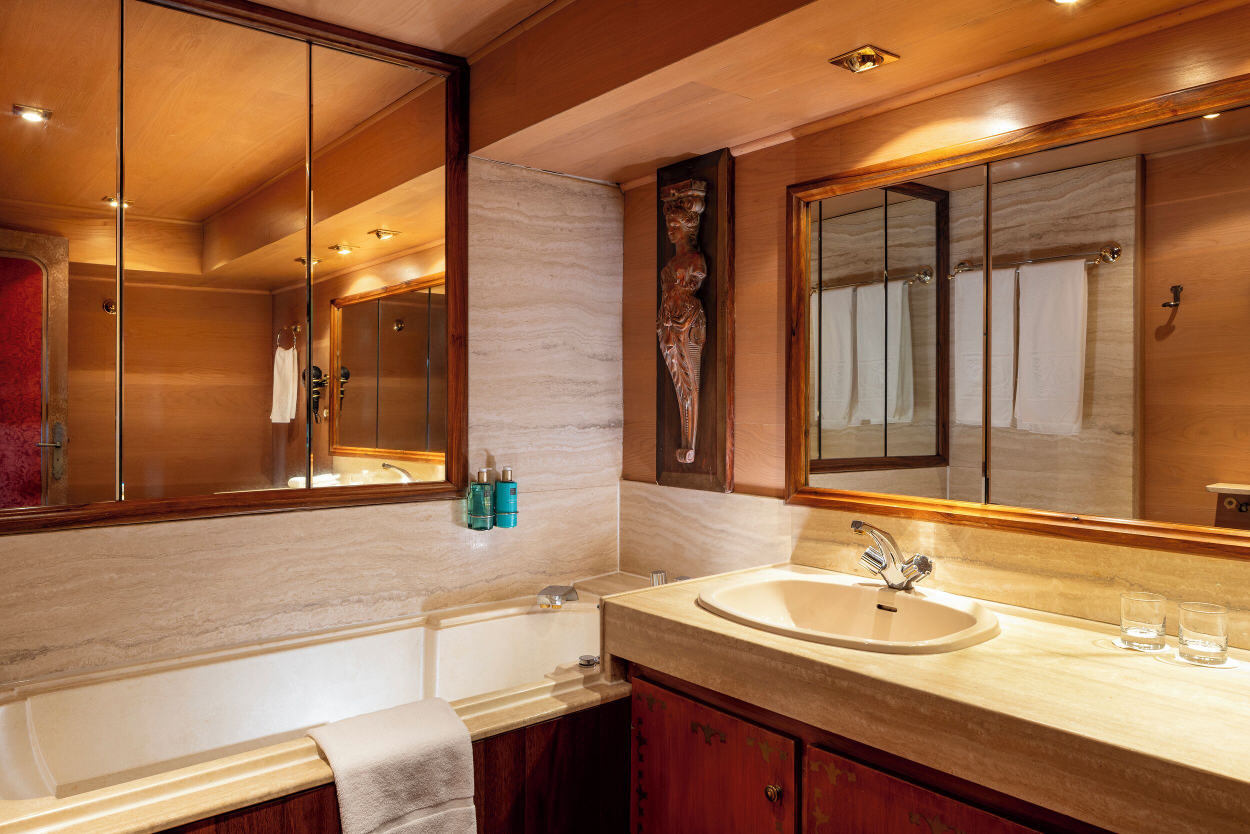 Un bagno moderno con uno specchio grande, una vasca, un lavandino e un mobile lavabo.