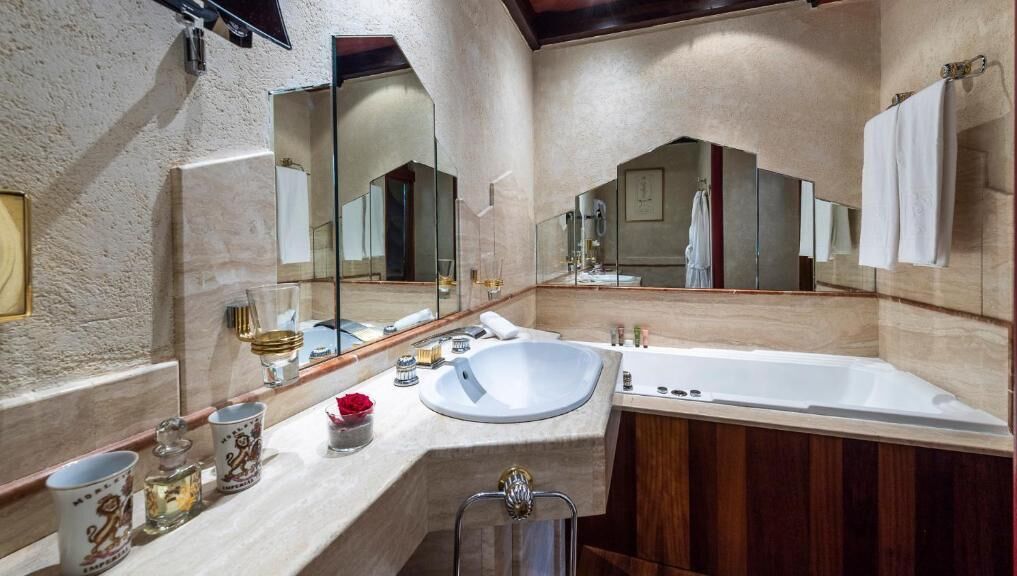 Een badkamer met een grote spiegel, een wastafel en een bad.