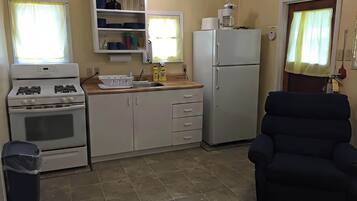 Een koelkast, een kookplaat, kookgerei, borden en bestek