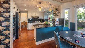 Une cuisine moderne dotée d’un îlot central, de planchers en bois et de luminaires suspendus.