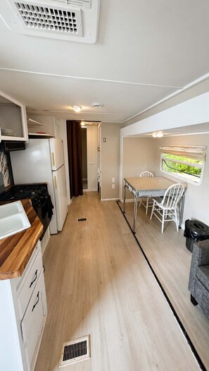 A compact kitchen with a dining area, a window with a view, and a small seating area. - Mill Lake Waterfront RV Retreat | Parry Sound #01 (Parry Sound)