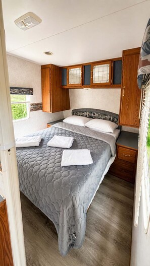 A bedroom with a bed, wooden cabinets, and a window. - Waterfront Family Retreat Near Mill Lake – Parry Sound #10 (Parry Sound)