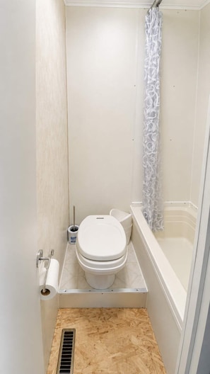 Une petite salle de bain compacte comprenant des toilettes, un bidet et une baignoire.