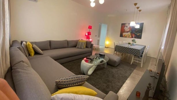 Una sala de estar con un sofá gris, una mesa de centro y un comedor con una mesa y sillas.