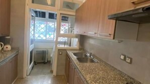 Una cocina con encimeras de granito, armarios de madera y un lavamanos de acero inoxidable.