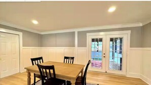 A dining room with a wooden table and four chairs, white paneled walls, and a door leading outside. - 1 Mile to Parris Island - 3BR Beaufort Home - Sleeps 6 (Beaufort)