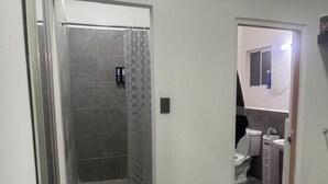 Casa de banho com chuveiro, sanita e lavatório.