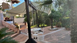 A patio area with outdoor seating and a pergola structure. - MODERN APARTMENT SURROUNDED BY GREENERY BUT A STONE'S THROW FROM THE SEA AND MOUNTAINS (Lazio)