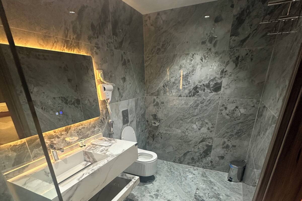 A modern bathroom with a glass-enclosed vanity, marble walls, and a shower area.