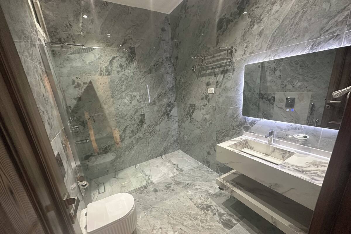 A modern bathroom with a marble floor, a freestanding bathtub, a large mirror, and a vanity with a sink.