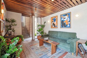 Una sala de estar moderna con un sofá verde, una mesa de centro de madera y diversas plantas.